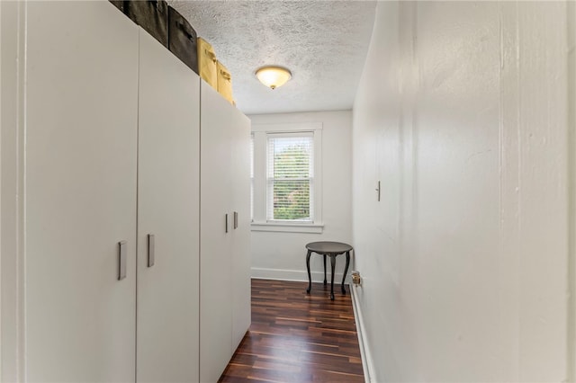 corridor featuring a textured ceiling and dark hardwood / wood-style floors