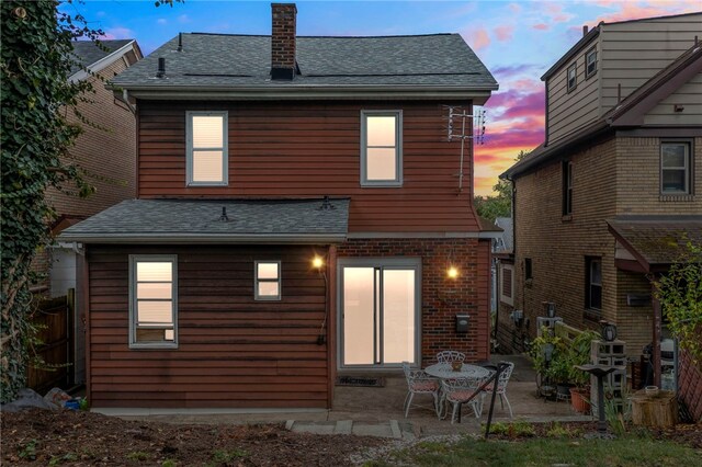 back house at dusk featuring a patio