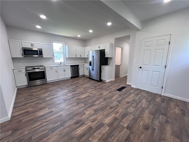 kitchen with appliances with stainless steel finishes, dark hardwood / wood-style floors, sink, and white cabinets