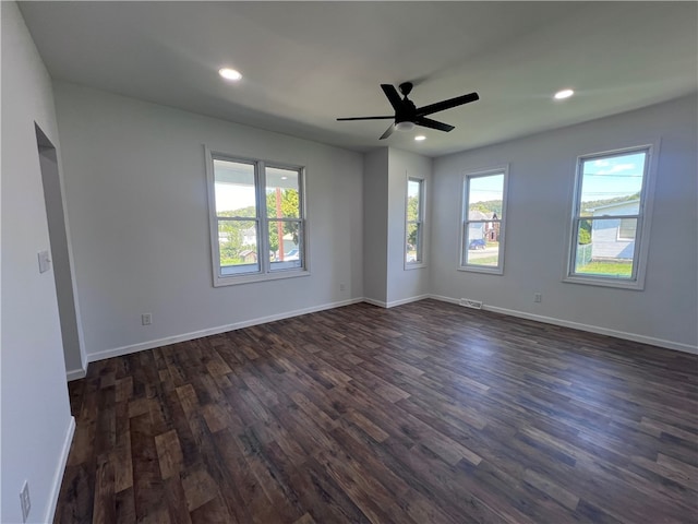 spare room with ceiling fan, plenty of natural light, and dark wood-type flooring