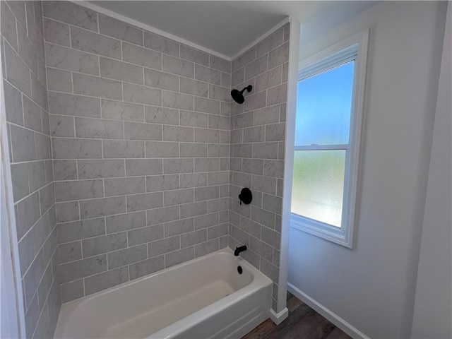 bathroom with wood-type flooring, tiled shower / bath, and ornamental molding