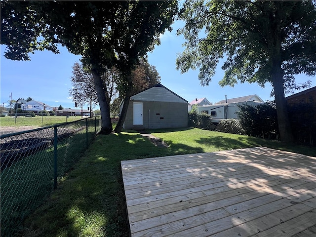 wooden terrace featuring a lawn and an outbuilding