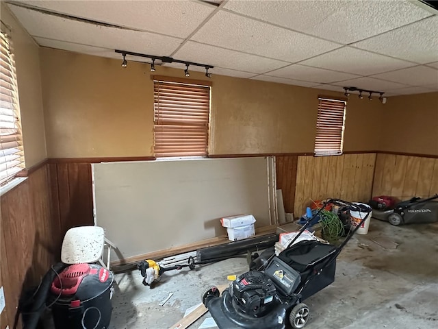 miscellaneous room with concrete flooring, track lighting, and a paneled ceiling