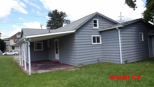 back of property featuring a carport and a yard