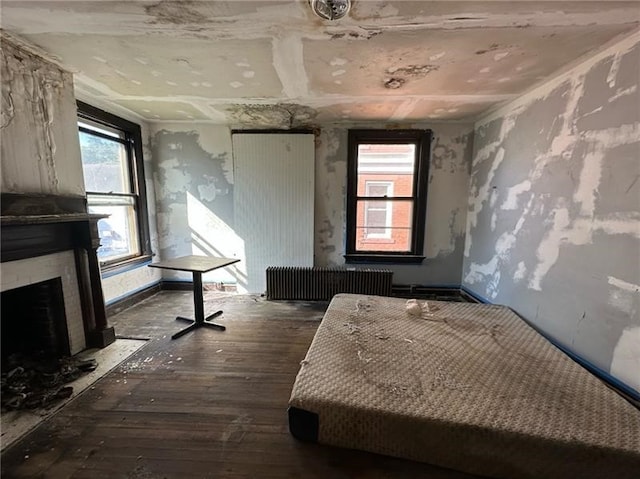 unfurnished bedroom with radiator heating unit and hardwood / wood-style floors