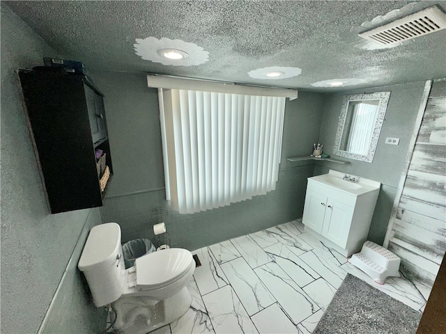 bathroom with tile flooring, a textured ceiling, toilet, and vanity