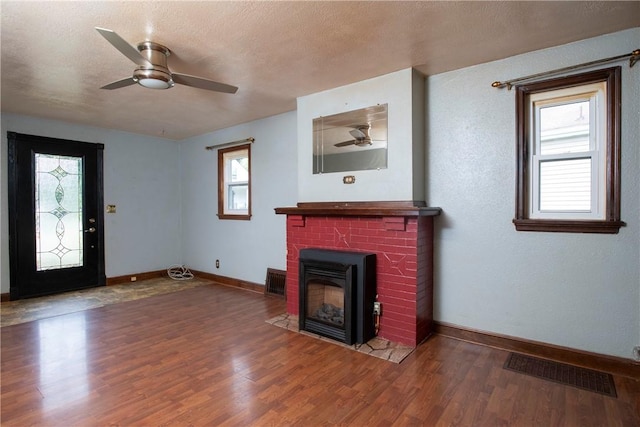 unfurnished living room with hardwood / wood-style flooring, ceiling fan, a fireplace, and a textured ceiling