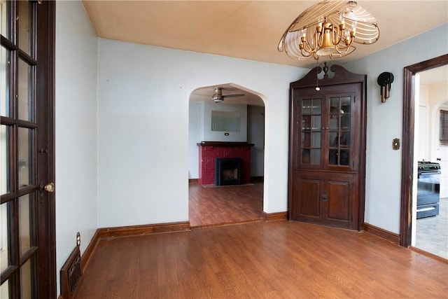 unfurnished dining area with hardwood / wood-style flooring, a fireplace, and a chandelier