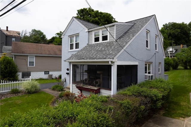 back of house with a sunroom and a lawn