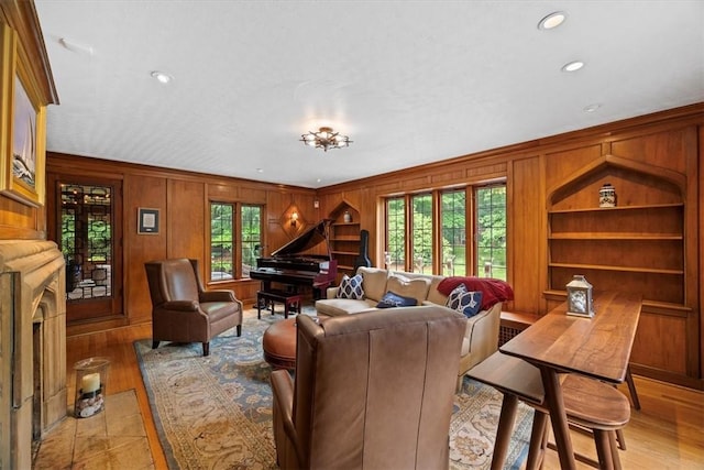 living room featuring light hardwood / wood-style floors, wooden walls, and built in shelves