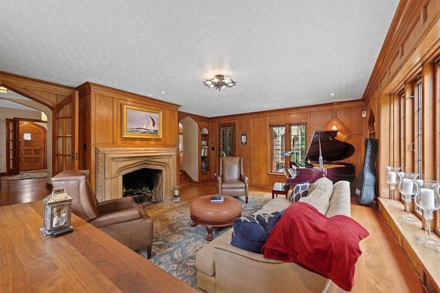 living room with ornamental molding, wooden walls, and light wood-type flooring