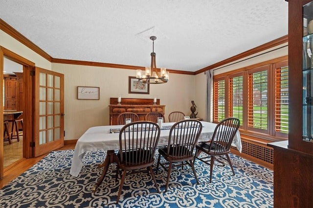 dining space featuring crown molding, a notable chandelier, a textured ceiling, and light hardwood / wood-style flooring