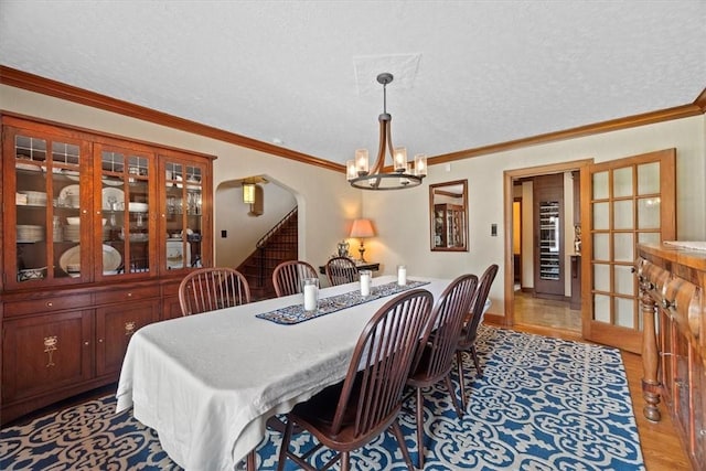 dining space with ornamental molding, a chandelier, light hardwood / wood-style flooring, and a textured ceiling