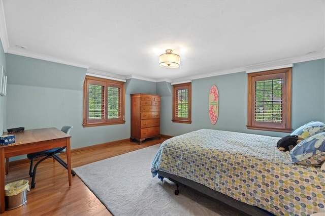 bedroom featuring multiple windows, wood-type flooring, and ornamental molding