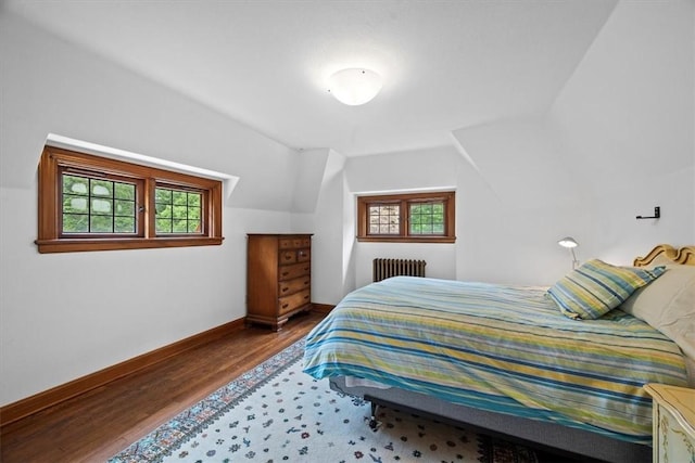 bedroom featuring lofted ceiling, radiator, and hardwood / wood-style flooring