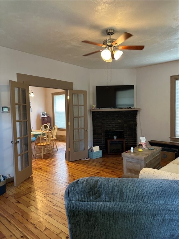 living room with ceiling fan, french doors, a fireplace, and wood-type flooring