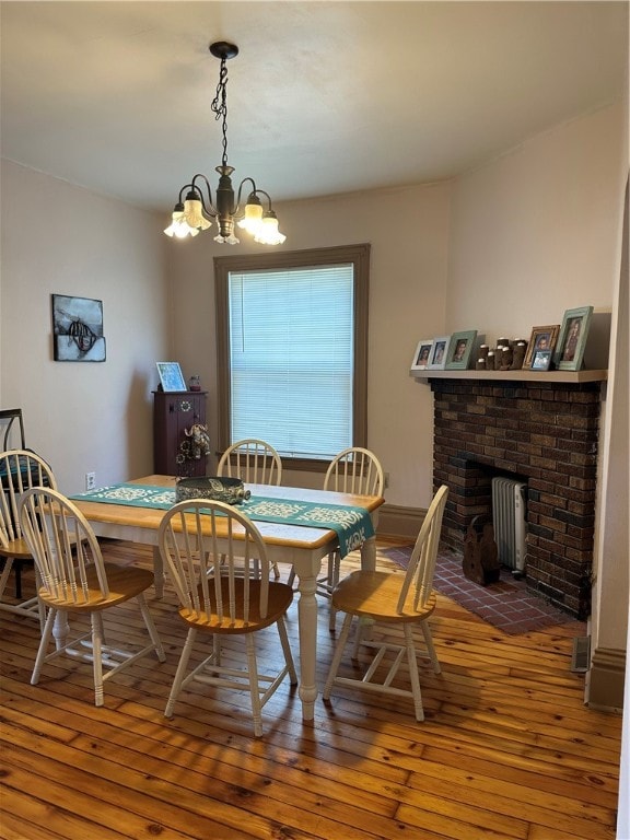 dining space featuring dark hardwood / wood-style floors, a fireplace, and a chandelier