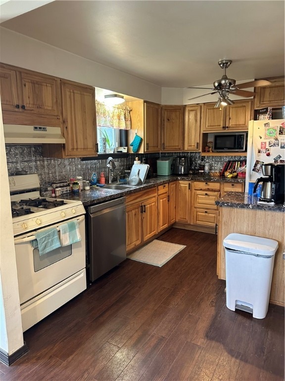 kitchen with appliances with stainless steel finishes, backsplash, ceiling fan, and dark hardwood / wood-style flooring