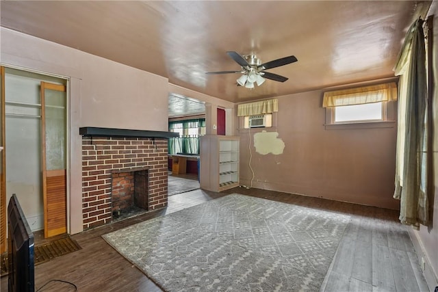 unfurnished living room with ceiling fan, cooling unit, wood-type flooring, and a fireplace