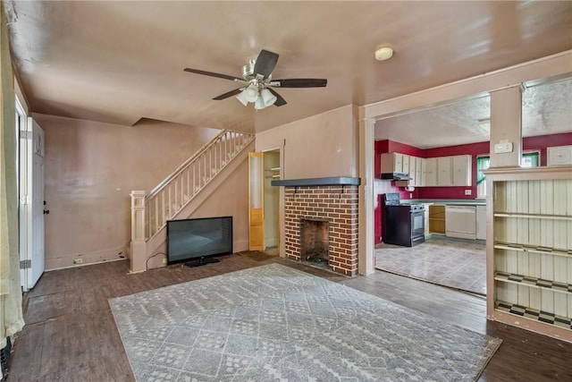 unfurnished living room with ceiling fan, dark hardwood / wood-style floors, and a brick fireplace