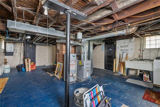 basement featuring electric panel, gas water heater, sink, washer / clothes dryer, and heating unit