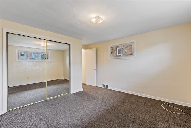 unfurnished bedroom with dark carpet and a closet