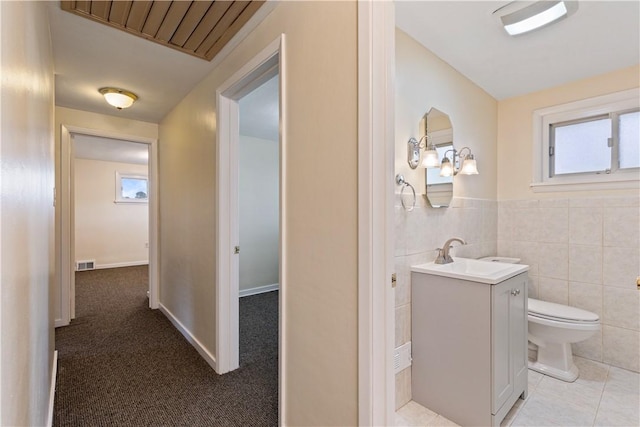 bathroom with vanity, toilet, and tile walls