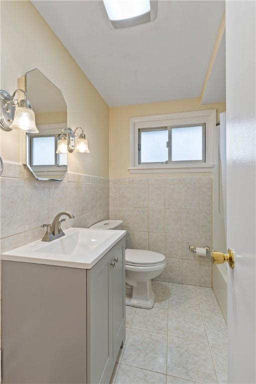 bathroom with tile patterned floors, vanity, toilet, and tile walls