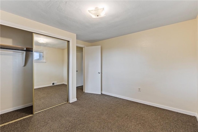 unfurnished bedroom with a closet and dark colored carpet