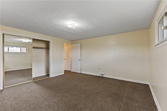 unfurnished bedroom with dark carpet and a closet