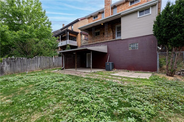 rear view of property with a lawn, central AC unit, and a patio area