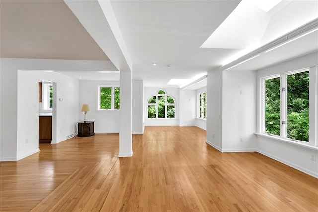 unfurnished living room featuring light hardwood / wood-style floors and a skylight