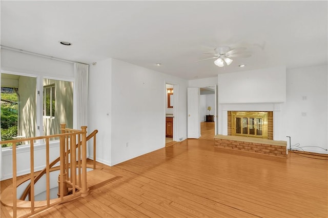 living room with ceiling fan, light hardwood / wood-style floors, and a brick fireplace