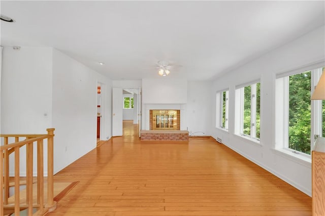 unfurnished living room featuring light hardwood / wood-style floors, a brick fireplace, and ceiling fan