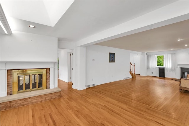 unfurnished living room featuring a fireplace, a baseboard radiator, and light hardwood / wood-style flooring