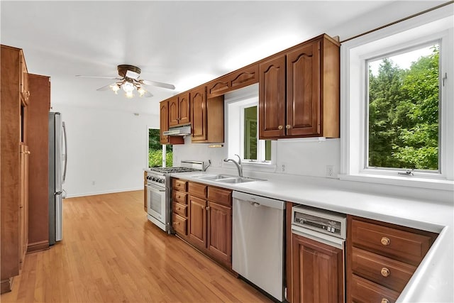 kitchen featuring ceiling fan, sink, stainless steel appliances, and light wood-type flooring