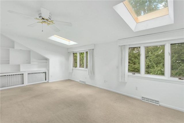 additional living space with light carpet, vaulted ceiling with skylight, and ceiling fan