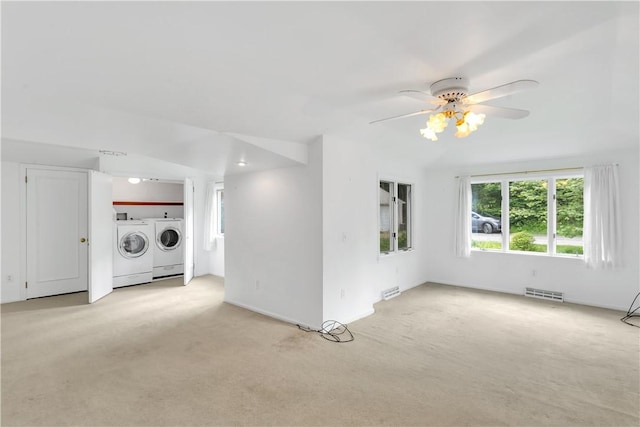 unfurnished living room featuring washing machine and dryer, light colored carpet, and ceiling fan