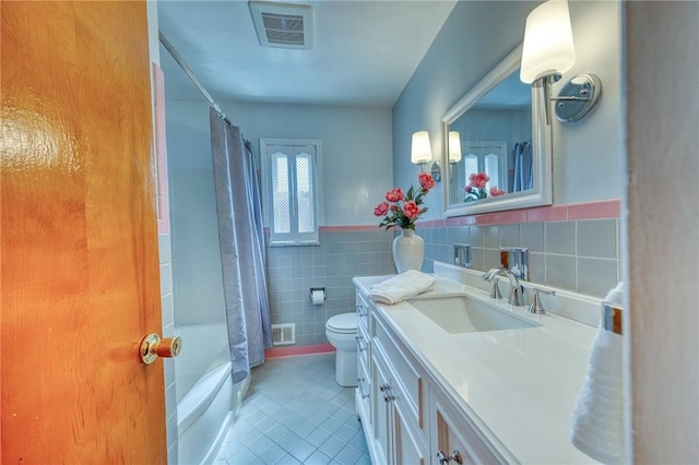 full bathroom featuring vanity, shower / bath combo with shower curtain, tile walls, tile patterned flooring, and toilet