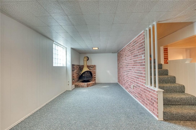 basement with carpet, a wood stove, and brick wall