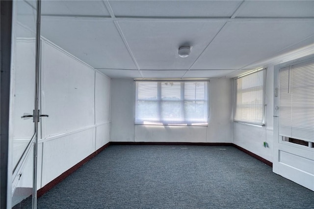 empty room with dark carpet and a drop ceiling