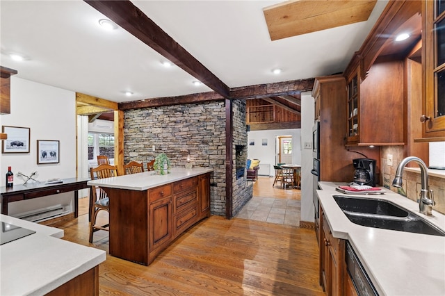 kitchen featuring a breakfast bar, sink, black dishwasher, beam ceiling, and light hardwood / wood-style floors