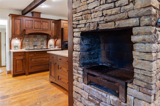 kitchen featuring tasteful backsplash, black electric stovetop, beam ceiling, and light wood-type flooring