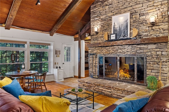 living room featuring beam ceiling, a stone fireplace, light wood-type flooring, and wood ceiling