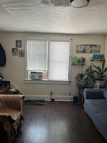 interior space featuring dark wood-type flooring, cooling unit, and a textured ceiling