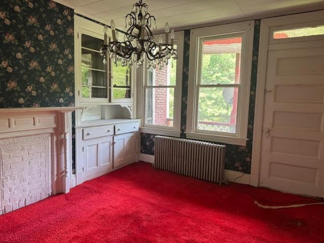 unfurnished dining area with carpet, radiator heating unit, and a chandelier