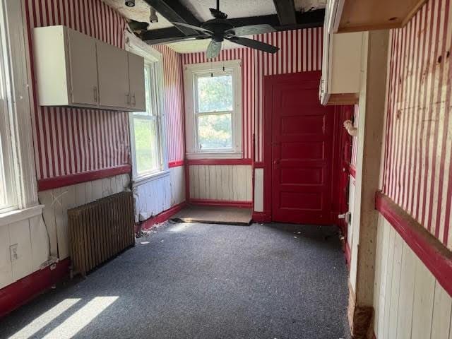 carpeted empty room featuring radiator and ceiling fan