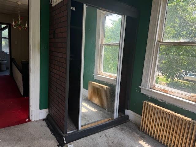 misc room featuring radiator heating unit, a chandelier, and carpet flooring