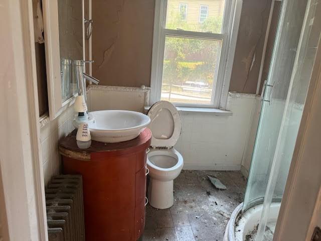 bathroom featuring vanity, toilet, radiator heating unit, and an enclosed shower