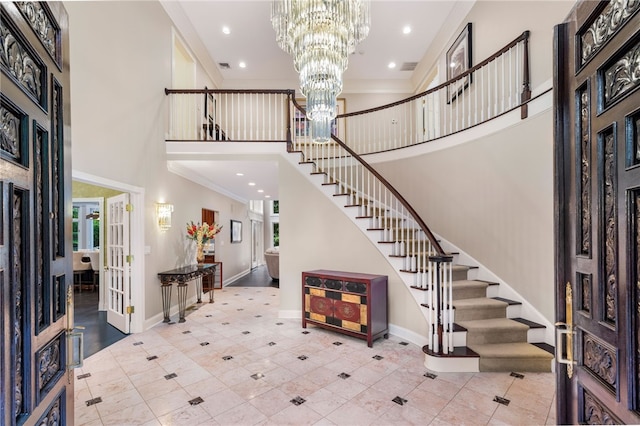 tiled entryway with ornamental molding, a towering ceiling, french doors, and a notable chandelier